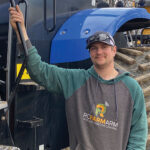 Jonah McGrath stands beside his farming tractor.