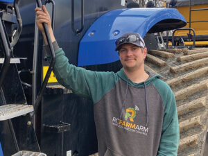 Jonah McGrath stands beside his farming tractor.