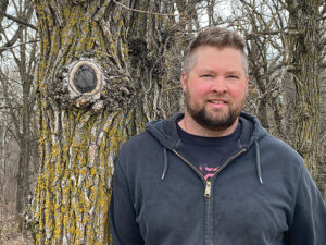 Owen Orsak stands in a forest.