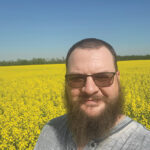 Ryan Gauthier stands in a field of yellow canola flowers.