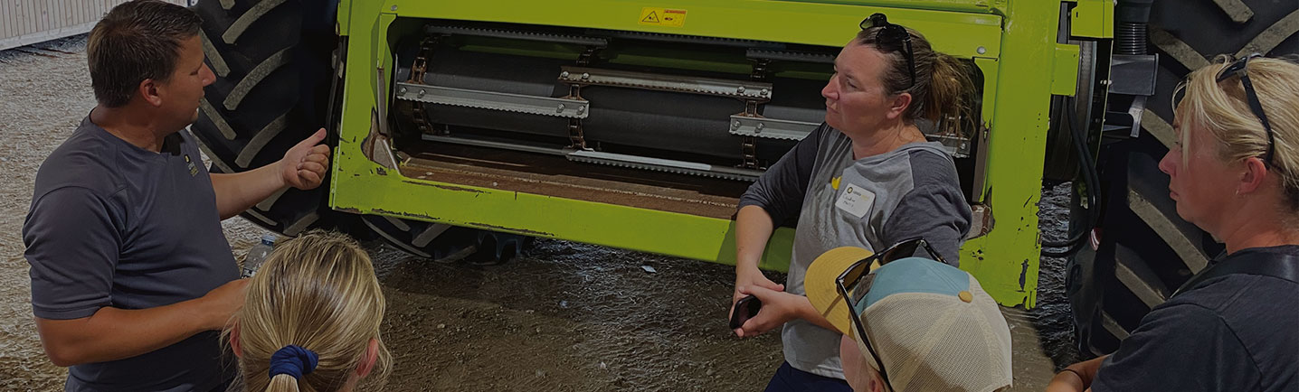 canola farmers chat in front of a large tractor-like machine