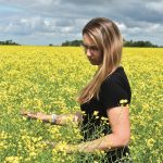 Andrea De Roo wades into a tall field of Canola.