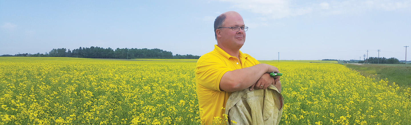 Agronomist Keith Gabert stands in a yellow field of canola